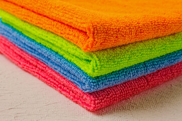 A stack of colored cloth , microfiber, for cleaning the house, on a white table, horizontal, no...