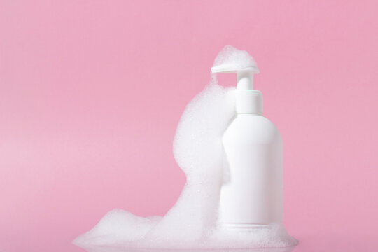 Cosmetics for face, body and hair care. Moisturizer, shampoo or facial cleanser on pink background with foam
