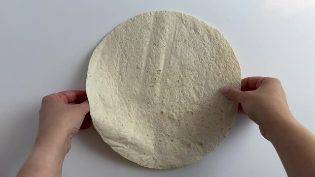 separating two tortilla wraps with hands in the frame