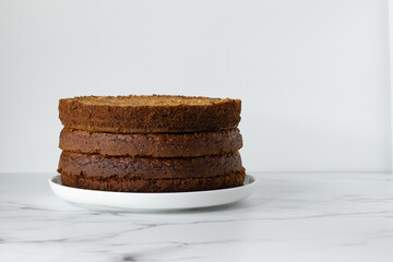 Preparation of layered carrot cake. Layers on a white plate on a marble table. White background, copy space