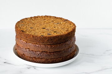 Preparation of layered carrot cake. Layers on a white plate on a marble table. White background, copy space