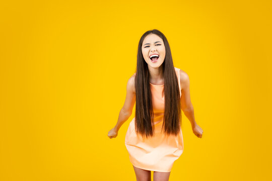 Nervous screaming young woman on a yellow backdrop, copy space.