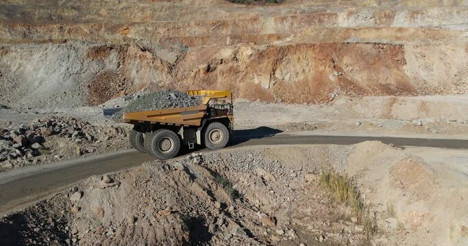 Aerial view of a mining truck is driving an iron ore mine loaded with ore.