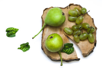 A bunch of grapes and wild pears on a wooden board on a white background. Close-up