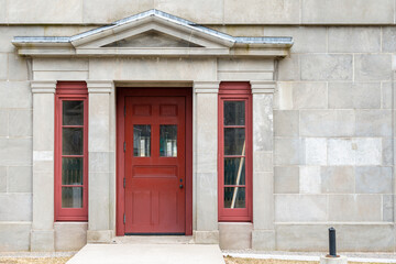 A wide vintage red wooden door with two glass pane windows on the top and panels on the bottom....