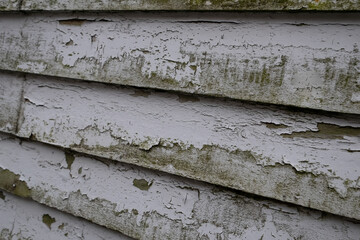 A horizontal wooden exterior wall, white color, of textured rough clapboard siding.  The wood is...