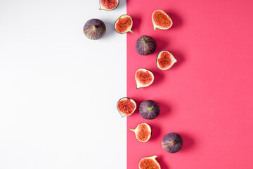 Pattern made of fresh ripe figs on pink and white background. Flat lay, top view of fresh ripe sliced figs on table.