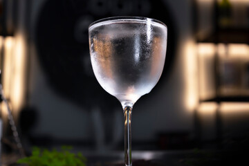 A misted glass of refreshing alcoholic drink on a bar counter. Close-up. Selective focus.