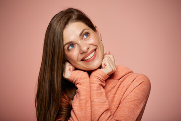 Woman face with natural real skin. Isolated portrait on pink background of smiling girl leaned on hands looking up.