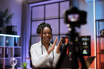 Smiling successful african american skilled businesswoman in formal wear recording new video for her internet business course and clapping hands.