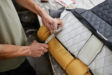 Close up of person fitting car upholstery and cutting extra threads with scissors, copy space