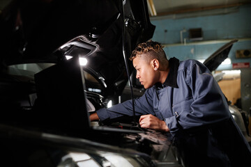 Side view portrait of female mechanic repairing truck engine in garage with accent light