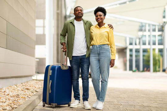 Cheerful Black Couple Hugging Posing With Suitcase Standing At Airport