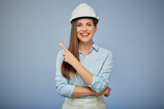 Woman architect or engineer in safety industrial helmet pointing with finger away. Isolated female portrait.