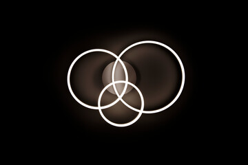 Chandelier luminous in the form of three rings against a black ceiling