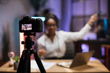 View of video camera screen with attractive confident african american skilled business woman explaining online economic charts on glass board to her colleagues.