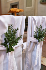 The backs of chairs for brides are decorated with periwinkle sprigs. Wedding traditions.