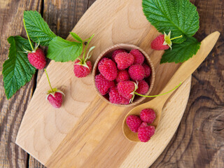 harvested red raspberries, large red garden raspberries in a wooden bowl on a wooden table