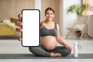 Happy Young Pregnant Woman Practicing Yoga At Home And Demonstrating Blank Smartphone