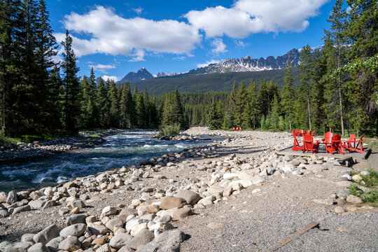 Red adirondack chairs near a creek along the Bow Valley Parkway in Banff National Park Canada