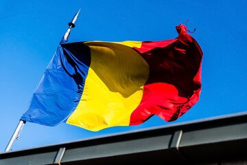 Romania flag blowing in wind isolated on blue sky.