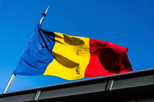 Romania flag blowing in wind isolated on blue sky.