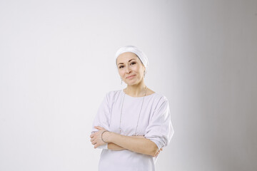 Portrait of a girl in a hijab in white clothes against a white background