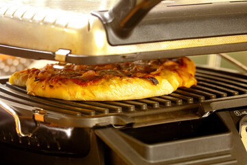 Heat a pizza from the day before under a contact grill - 532029091