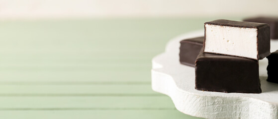 Tasty bird's milk candies on wooden table, closeup. Banner for design