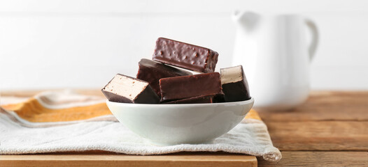 Bowl with tasty bird's milk candies on wooden table