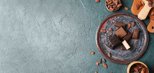 Plate of tasty bird's milk candies and cocoa beans on grey background with space for text, top view