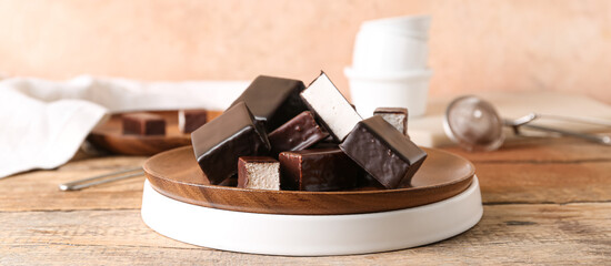 Plate with tasty bird's milk candies on wooden table