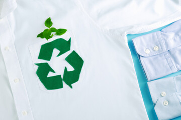 Recycling arrow symbol made from green felt on background of a white shirt. Ecological and...