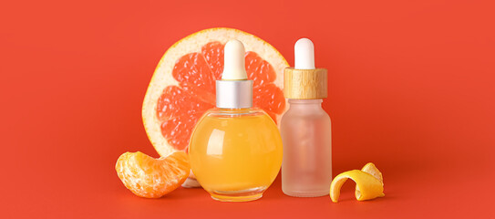 Bottles of citrus essential oil on red background