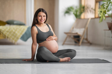 Portrait Of Beautiful Smiling Pregnant Woman Posing On Yoga Mat At Home