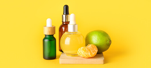 Bottles of citrus essential oil on yellow background