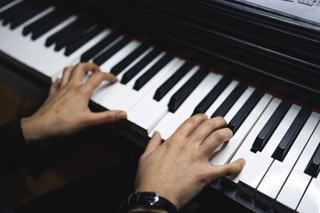Close up of woman's hands playing piano by reading sheet music. Selective focus