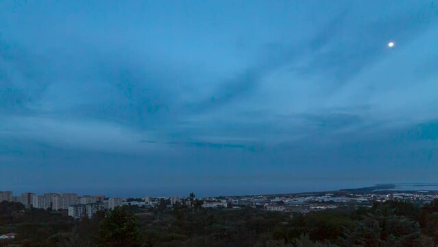 Time lapse shot of the sunset and moon rise over the city of Bastia with the Mediterranean Sea in the background. Clouds, stars and the moon move in the sky while the city gets illuminated