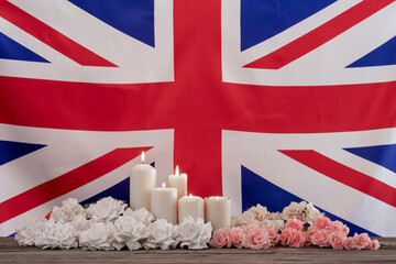 BRITISH FLAG, LIGHTED CANDLES AND FLOWERS ARRANGEMENTS. MEMORIAL, PRAY, CONDOLENCES, DEATH, FUNERAL...
