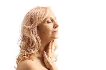 Profile shot of a mature woman with bare shoulders massaging her neck