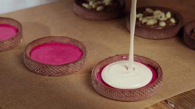 Chef adding white cream to the small tarts with chokolate