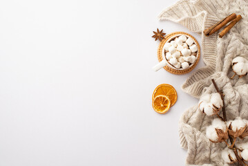 Top view photo of mug of hot drinking with marshmallow on rattan serving mat knitted plaid cotton branch dried orange slices anise and cinnamon sticks on isolated white background with copyspace