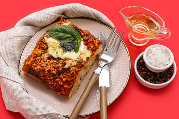 Plate of tasty Italian pie with mozzarella, pesto sauce, spices and oil on red background, closeup