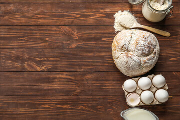 Fresh bread, eggs and flour on wooden background