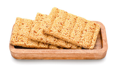 Wooden board with tasty sesame kozinaki on white background
