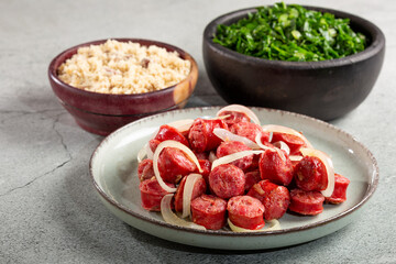 Sliced sausage with onion, green cabbage and farofa.