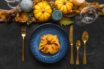 Beautiful table setting with pumpkins and candles on dark background