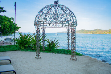 yacht framed by wrought iron gazebo on a sunset lit beach in Mexico