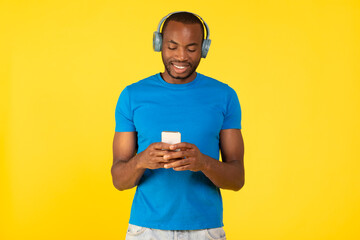 Black Guy Listening Music On Phone Wearing Headphones, Yellow Background