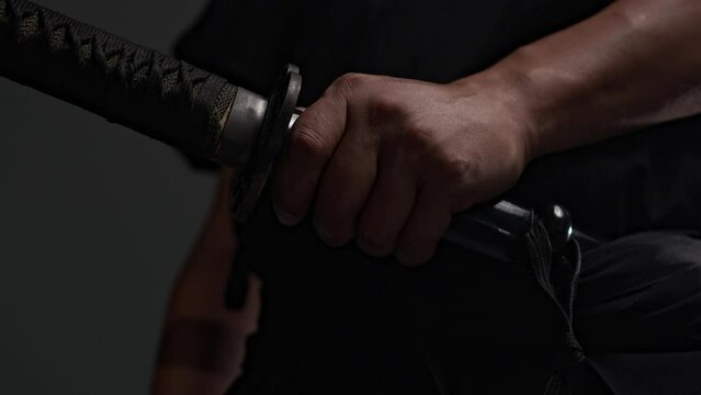 Japanese, black traditional kimano samurai, wars, touches sheath katana, runs fingers along sharp blade, braid handle. Kenjutsu national Japanese cultural identity historical traditions samurai studio